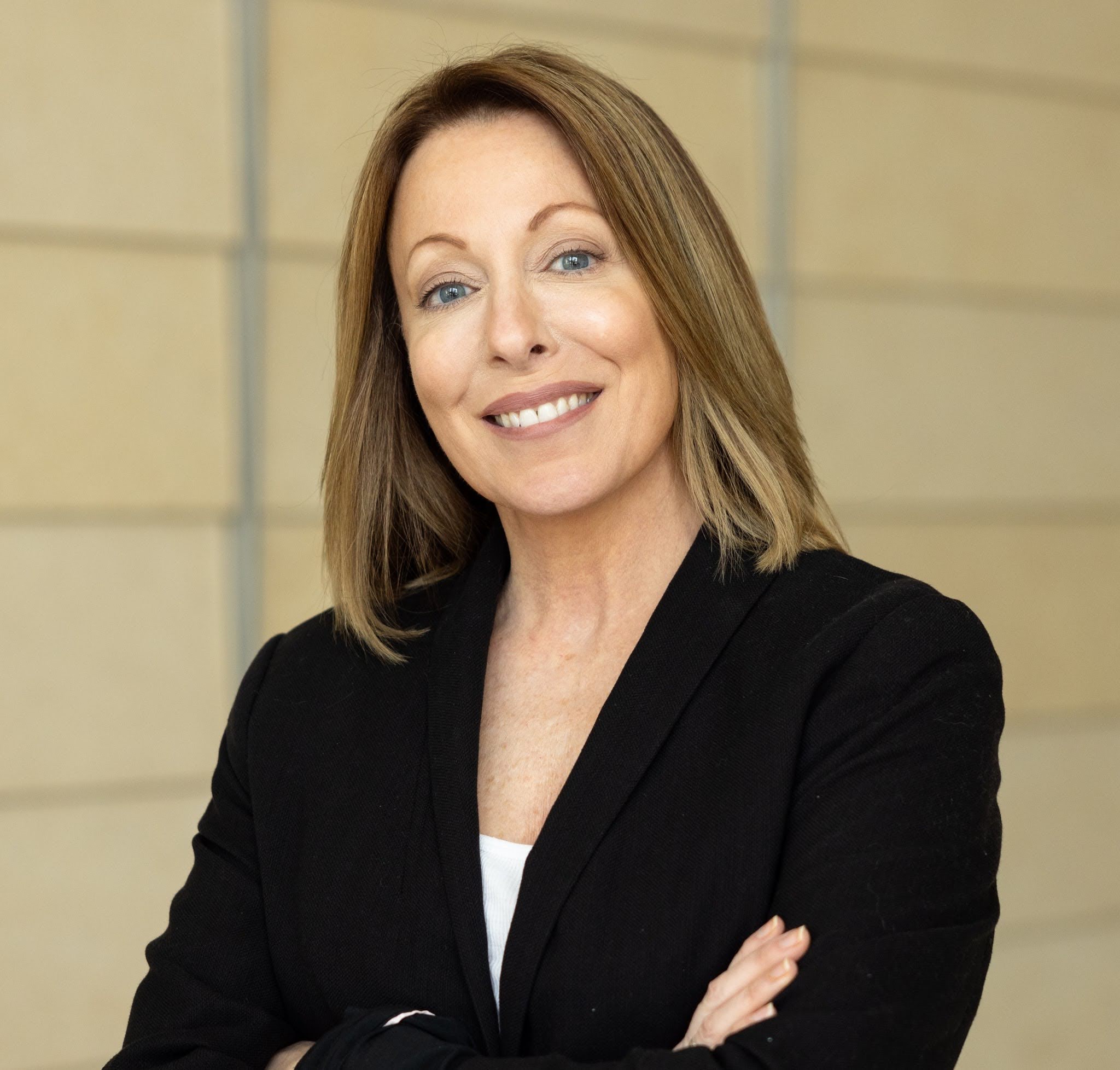 Portrait of a professional in a black blazer, smiling confidently at the camera.