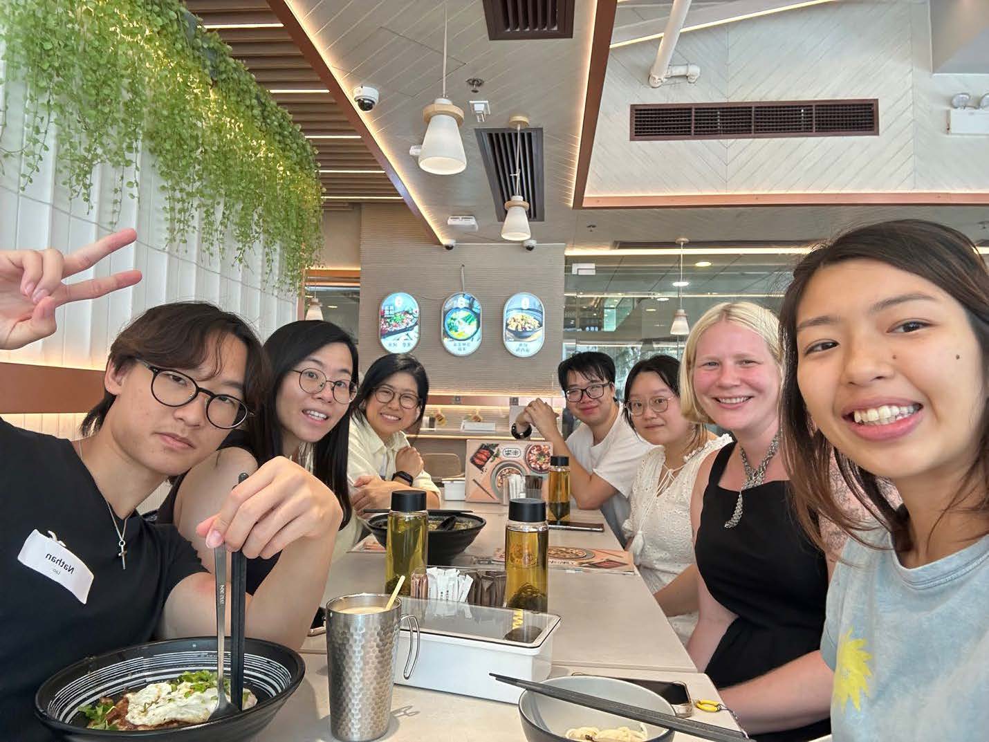 Group of people enjoying a meal together at a restaurant, smiling and making peace signs.