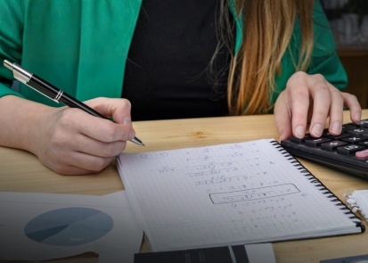 A high schooler solving math equations and checking her work with a calculator